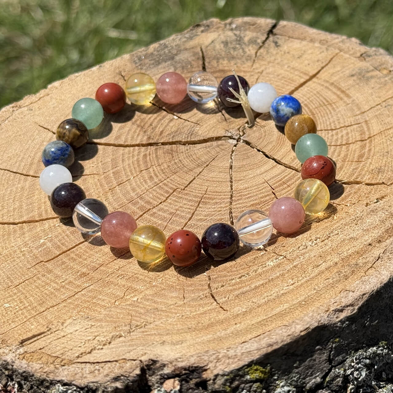 9 Planet crystal bracelet on wooden block with blurred garden background