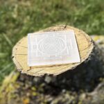 Side-angle view of Shree Yantra engraved Selenite charging plate on wooden block
