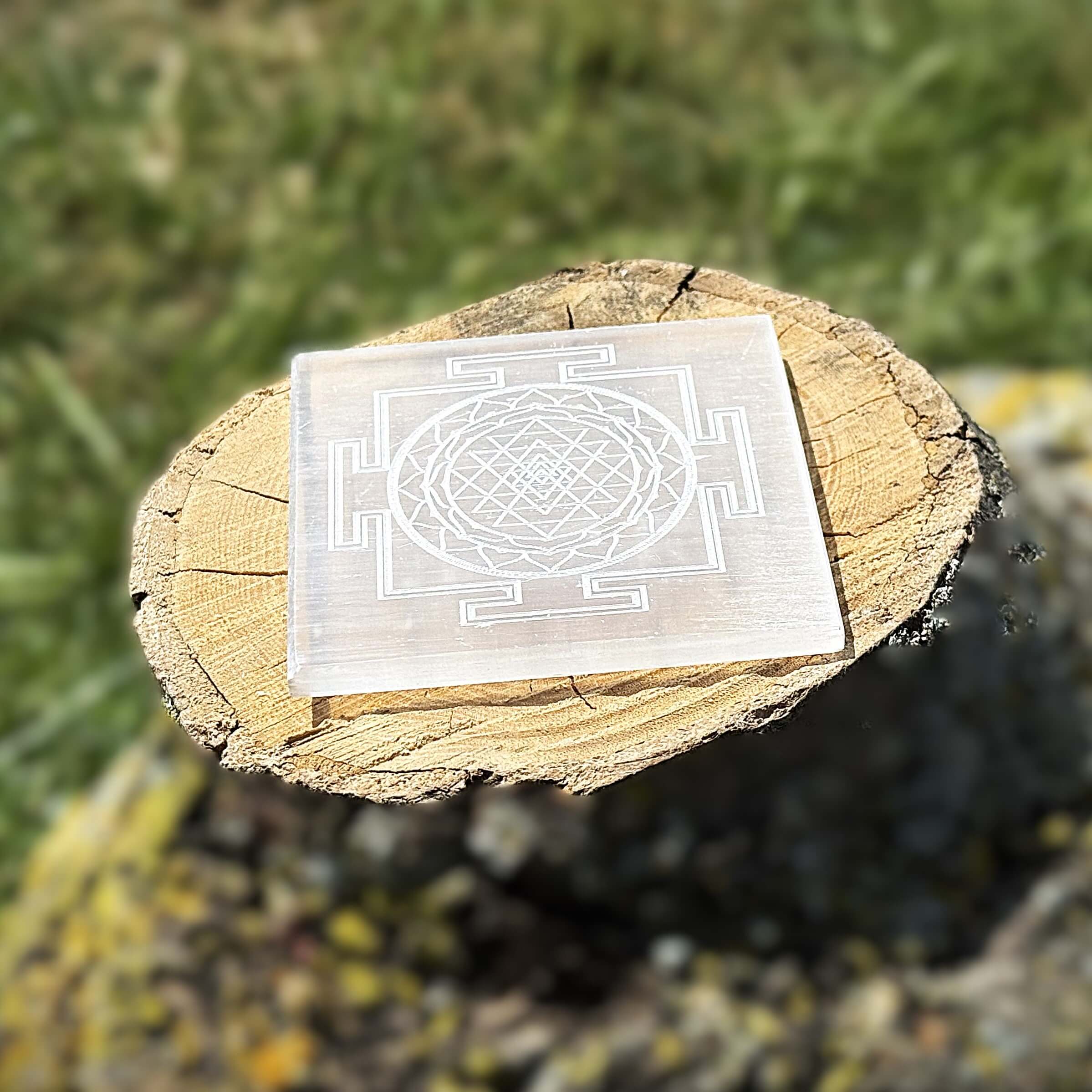 Side-angle view of Shree Yantra engraved Selenite charging plate on wooden block